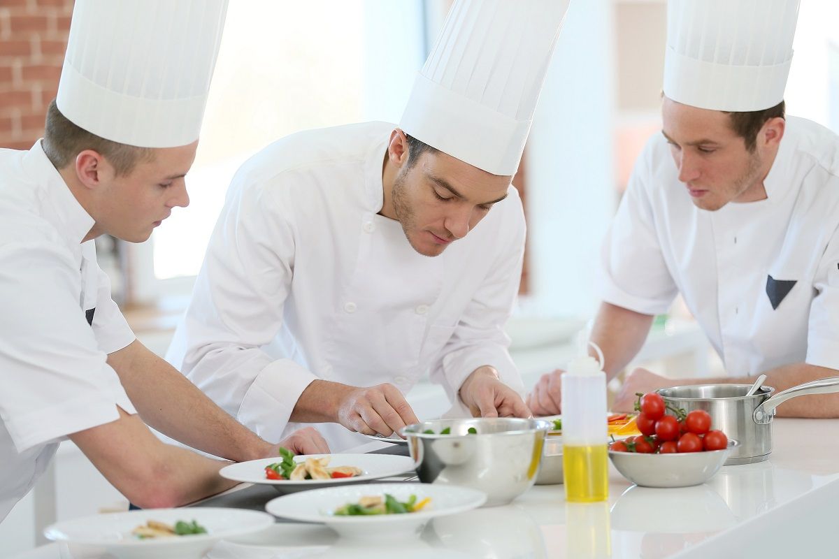 Chef training students in restaurant kitchen