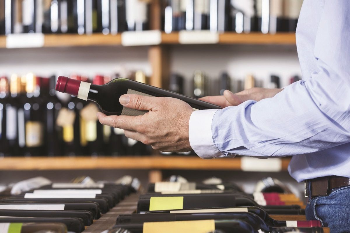 62419944 – midsection of male customer holding wine bottle in shop
