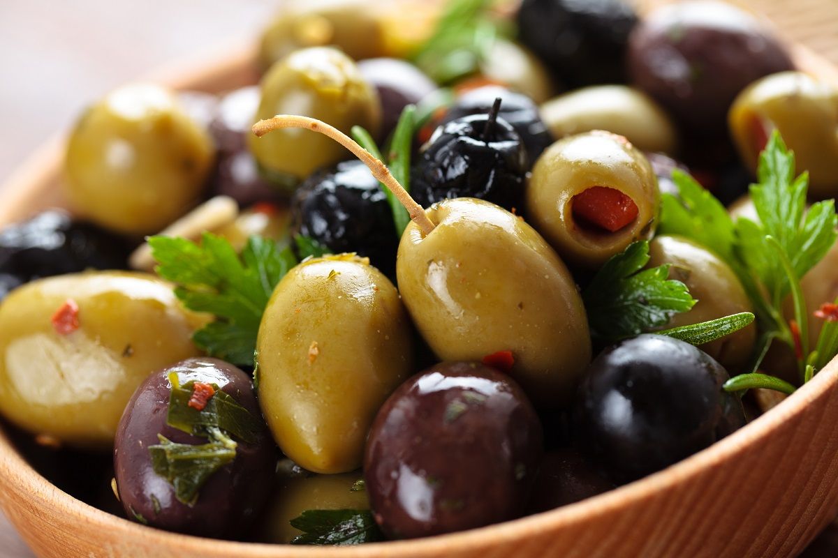 Marinated olives in wooden plate.