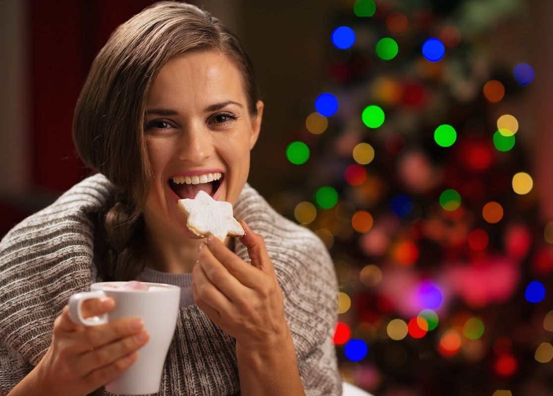 16192491 – happy woman eating christmas cookie and drinking hot chocolate