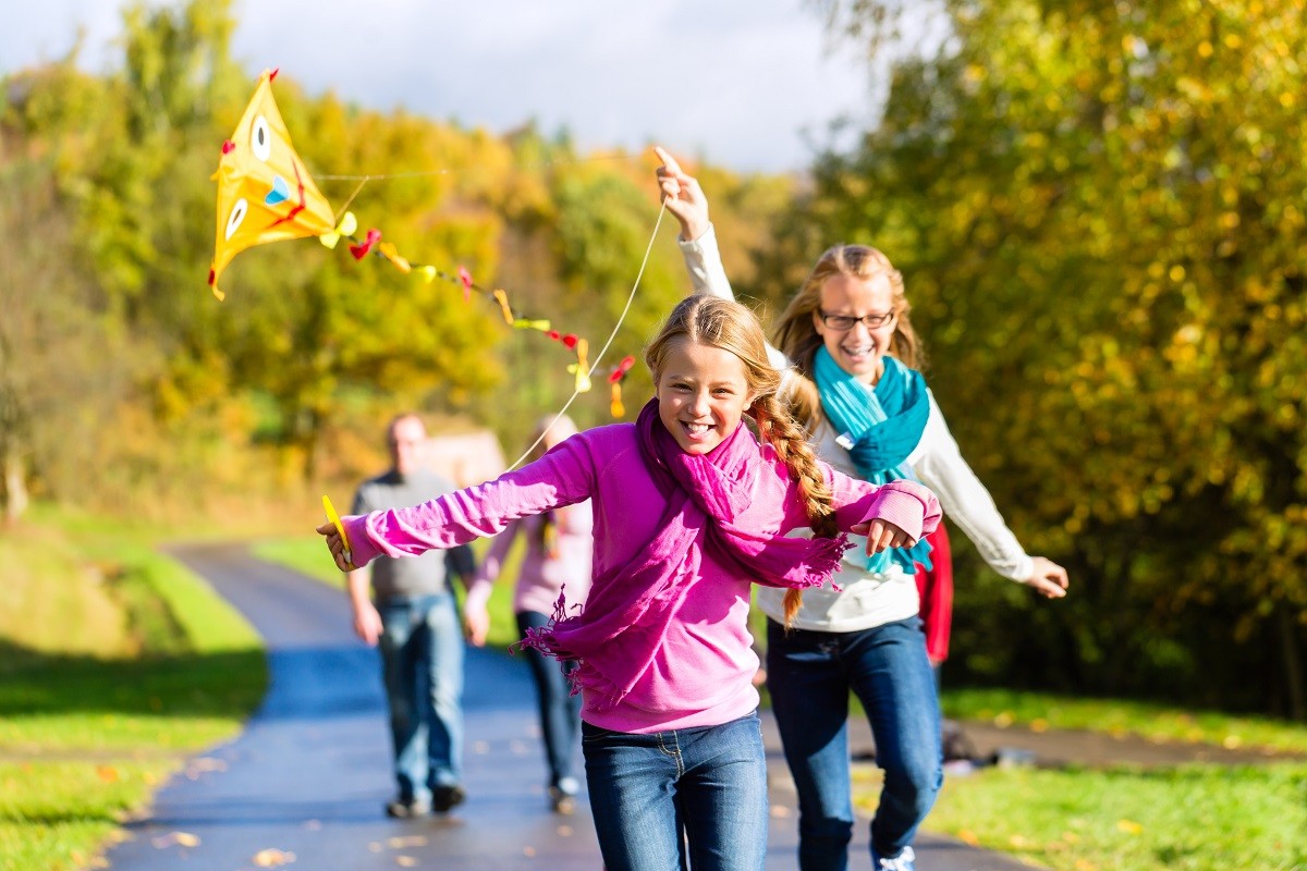 Family take walk in autumn forest flying kite