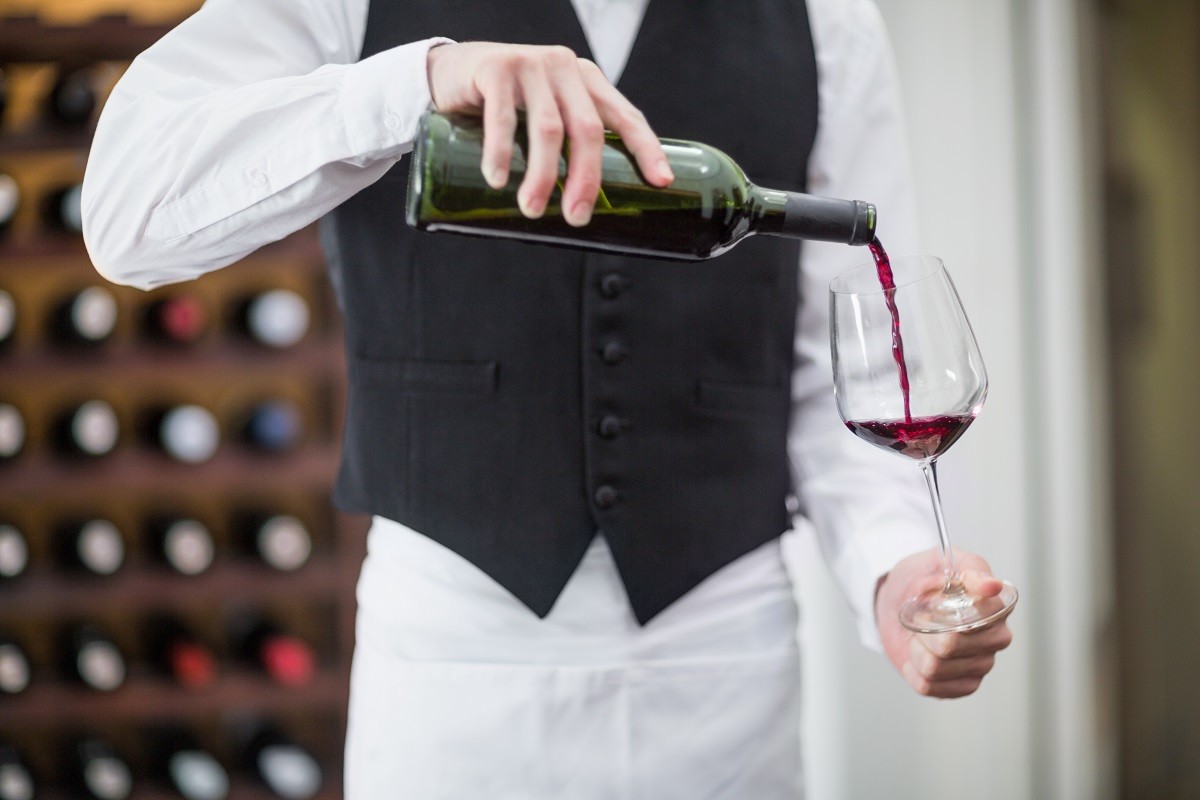 Male waiter pouring wine in wine glass