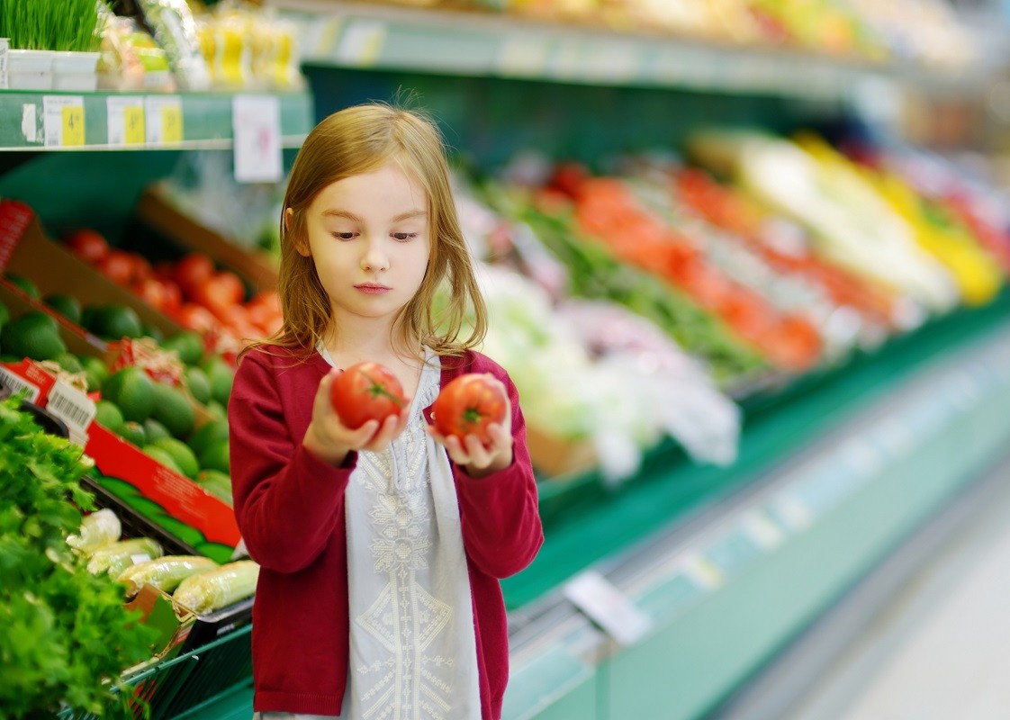 Little girl choosing tomatoes in a store