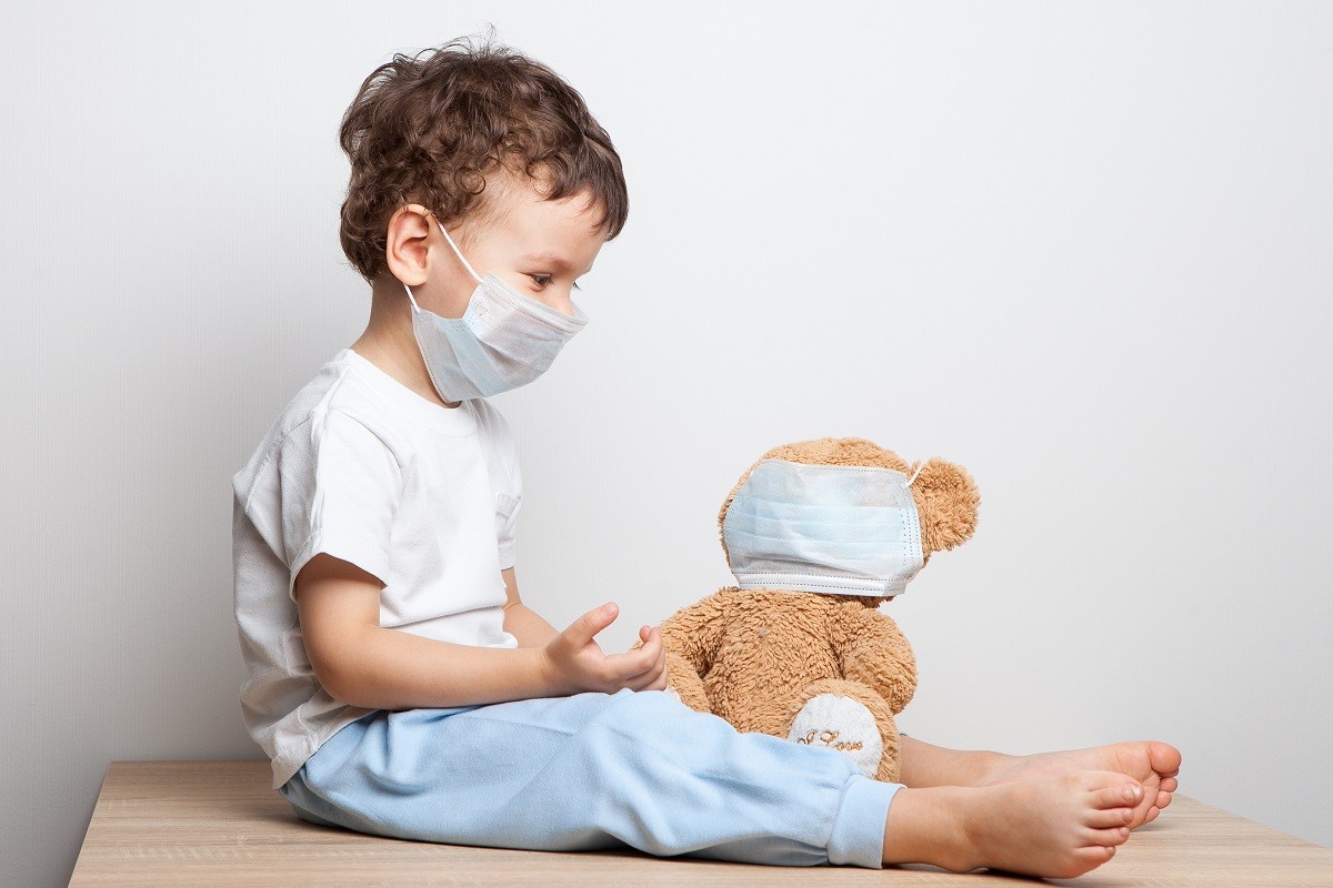 a child in a medical mask put on a respiratory mask for his favorite toy – a teddy bear. spread of coronavirus. hygiene. security measures . health care concept