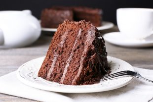 43129338 – delicious chocolate cake in white plate on wooden table , closeup