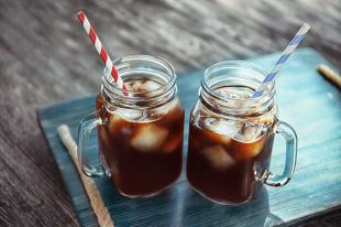 Mason jars with cold brew coffee on wooden tray