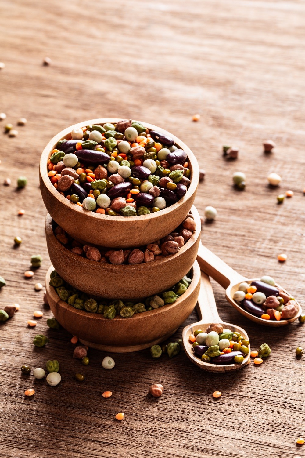 Mixed raw dried Indian legumes in wooden bowls on rustic backgro