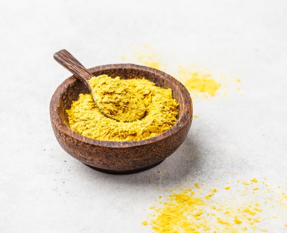 Nutritional yeast in a wooden bowl, copy space. Healthy vegan fo