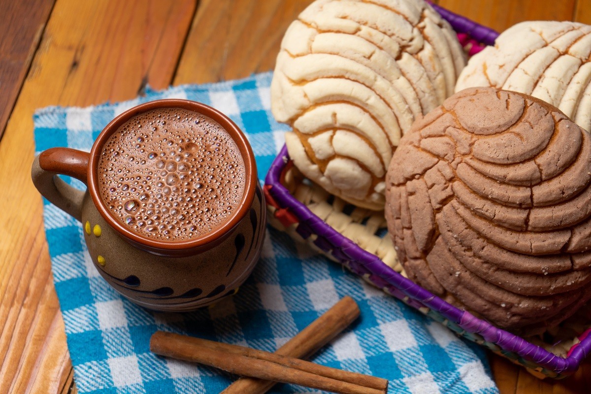Mexican hot chocolate with sweet conchas bread on wooden backgro