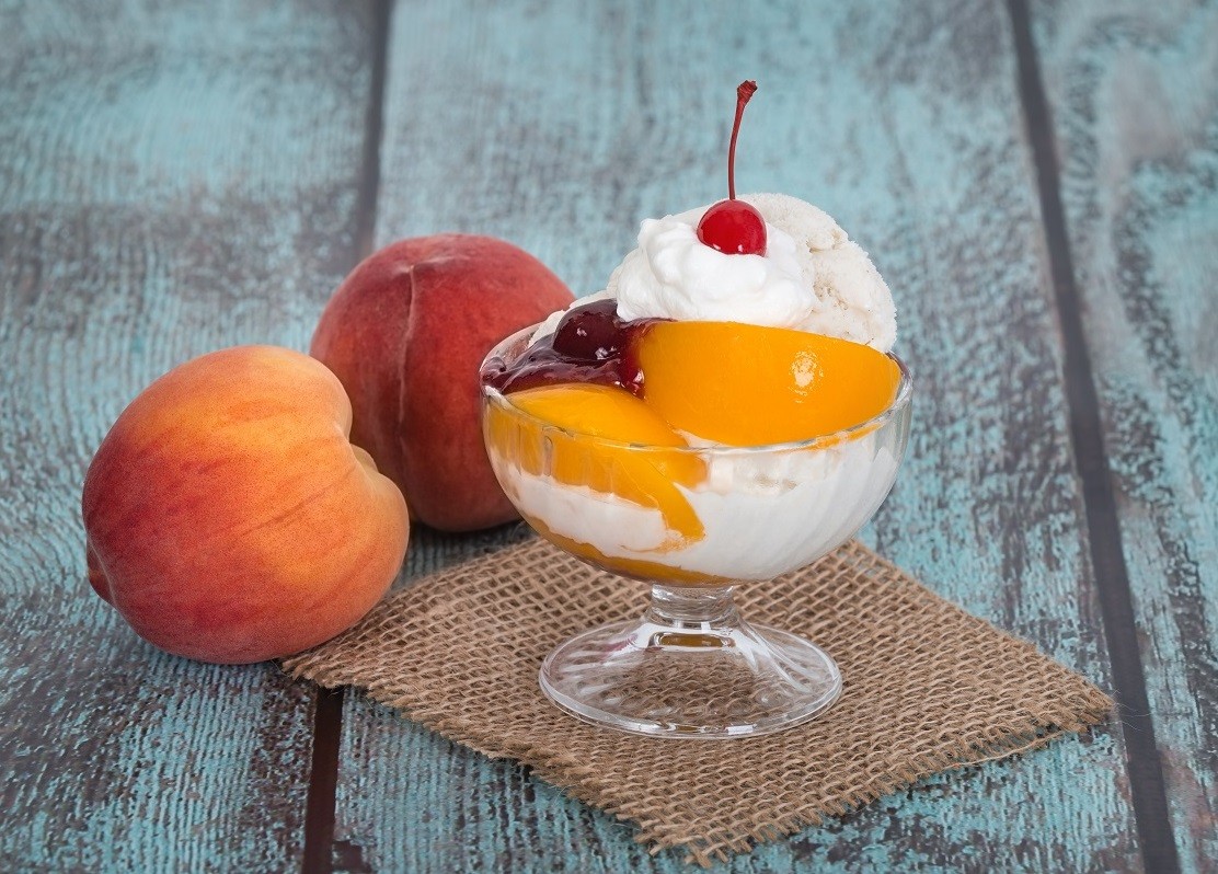 Vanilla peach melba ice cream with peach fruits on wooden vintag
