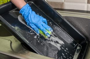 Housekeeper washes a baking dish with dishwashing liquid
