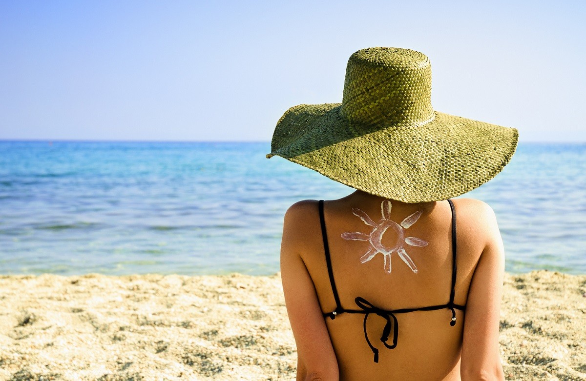 Woman on beach with sun symbol on her back – UV protection concept