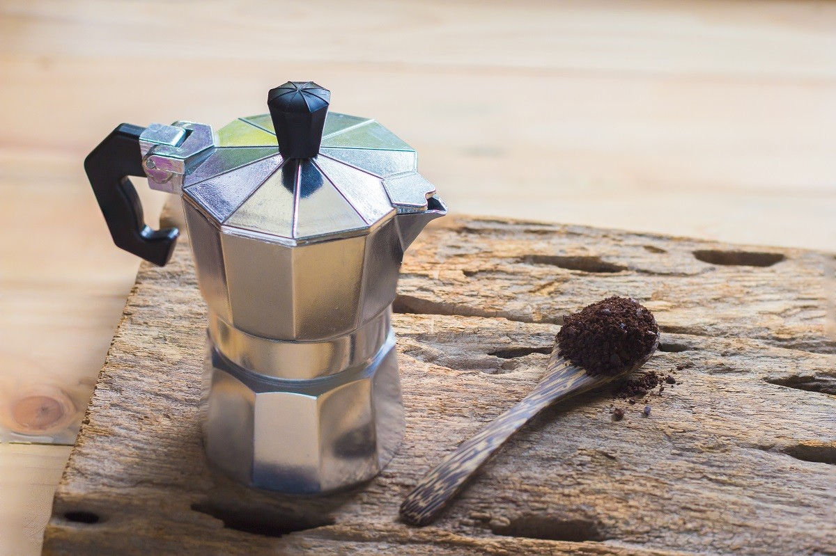 Moka pot and coffee on the wooden spoon.