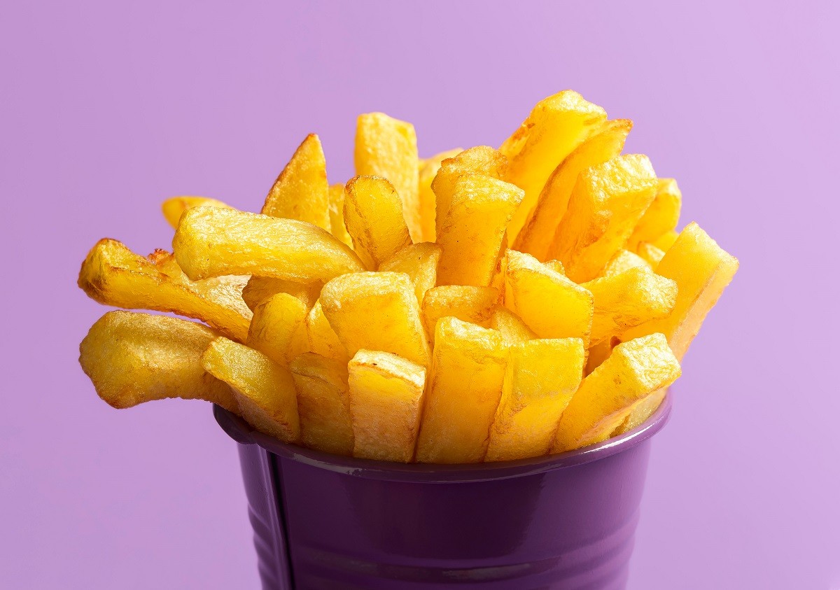 French fries close-up. Deep-fried food. French fries on purple b