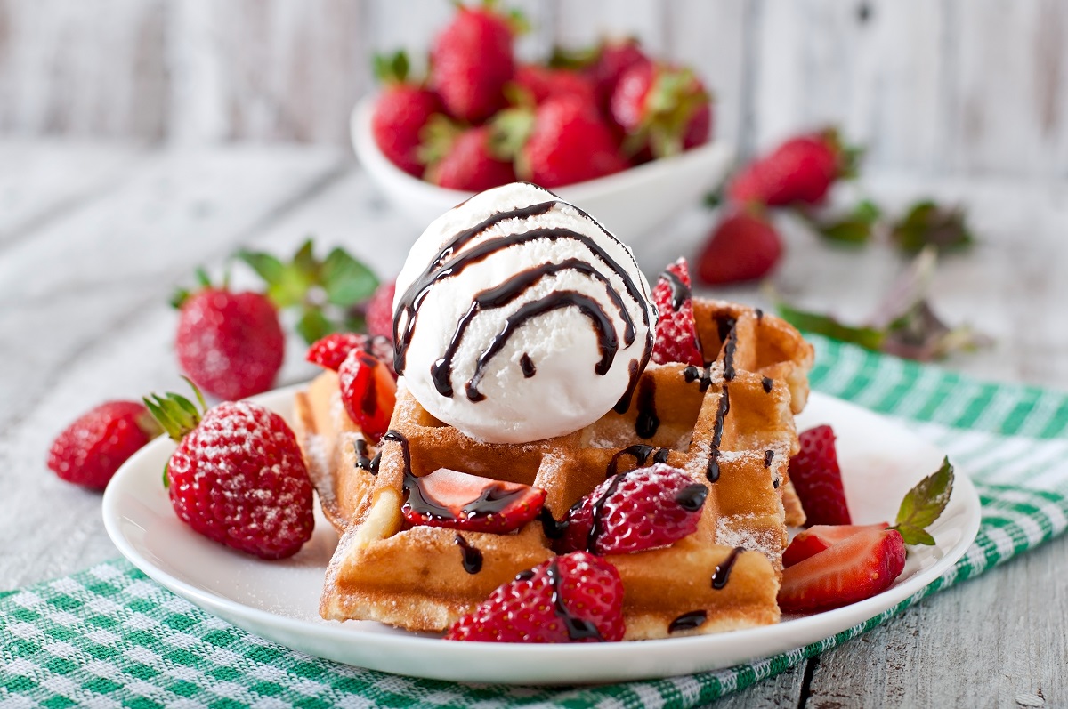 Belgium waffles with strawberries and ice cream on white plate