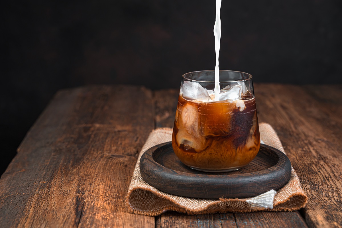 Iced coffee with milk, cold drink in a glass on a dark background.