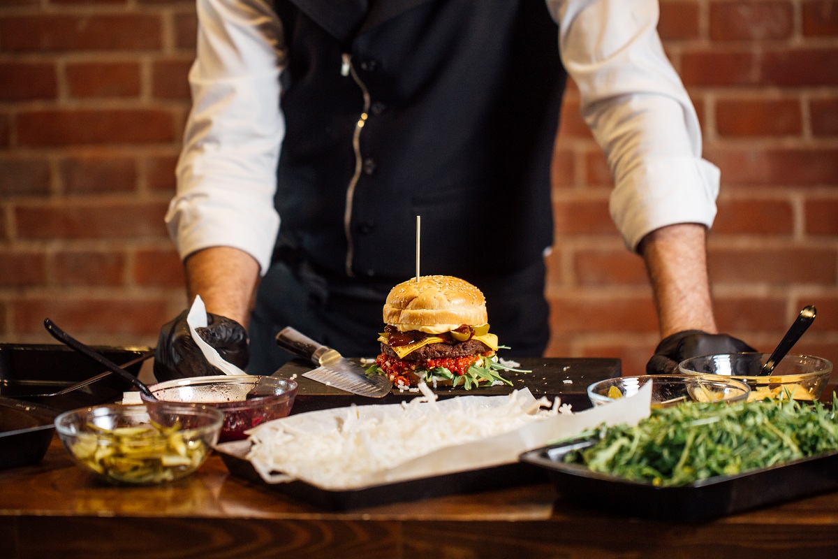 The chef prepares a Burger with beef, salad and vegetables.