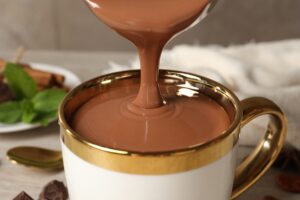 Pouring,Yummy,Hot,Chocolate,Into,Cup,On,Table,,Closeup