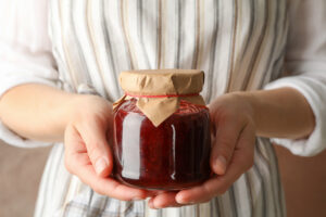 Woman,Holds,Glass,Jar,With,Strawberry,Jam,,Close,Up