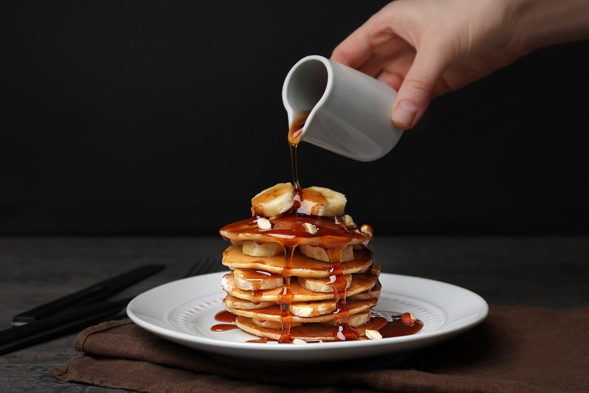 Woman,Pouring,Maple,Syrup,On,Tasty,Pancakes