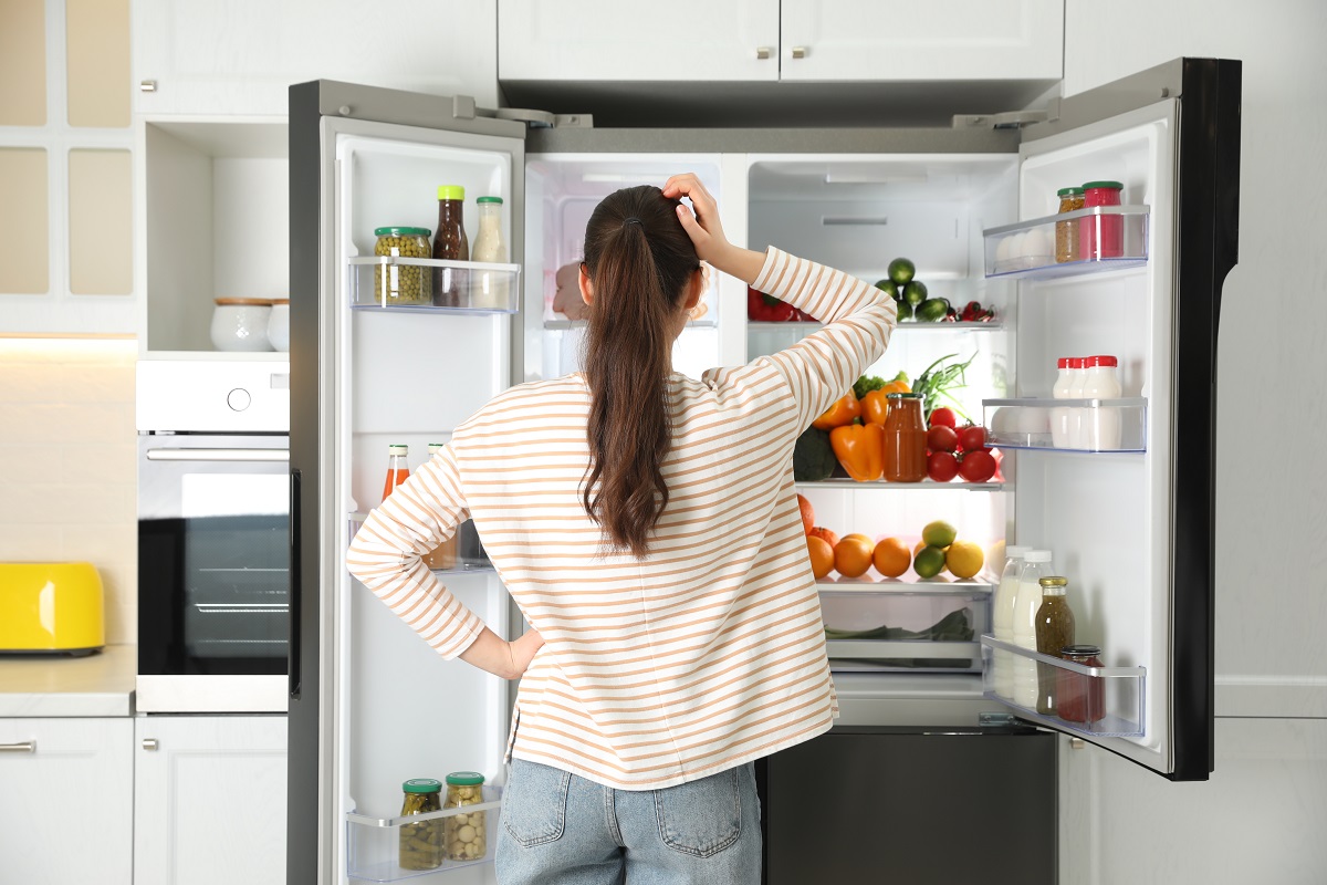 Young,Woman,Near,Open,Refrigerator,In,Kitchen,,Back,View