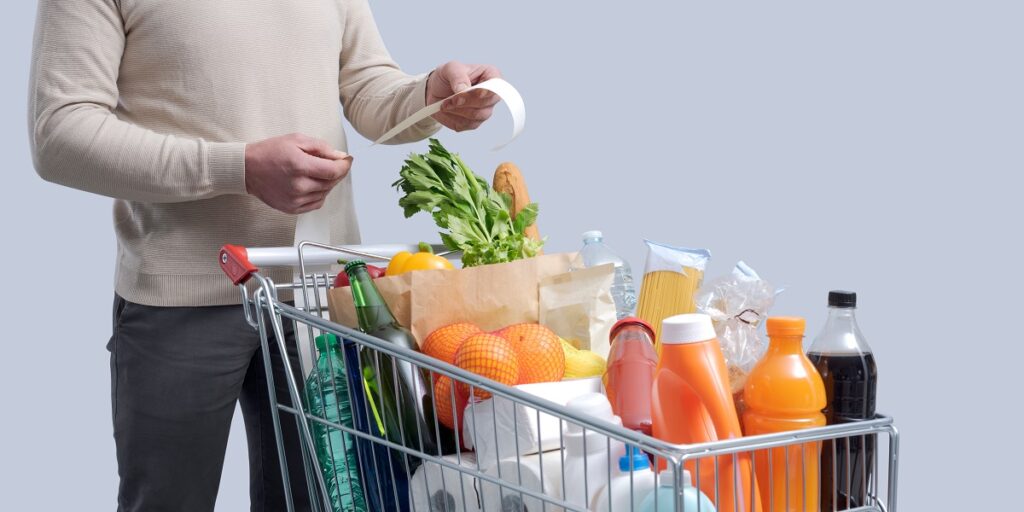Man,Standing,Next,To,A,Full,Shopping,Cart,And,Checking
