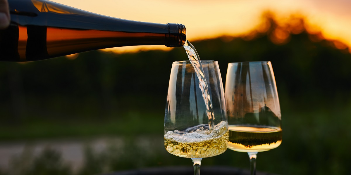 Pouring,White,Wine,Into,Glasses,In,The,Vineyard,At,Sunset