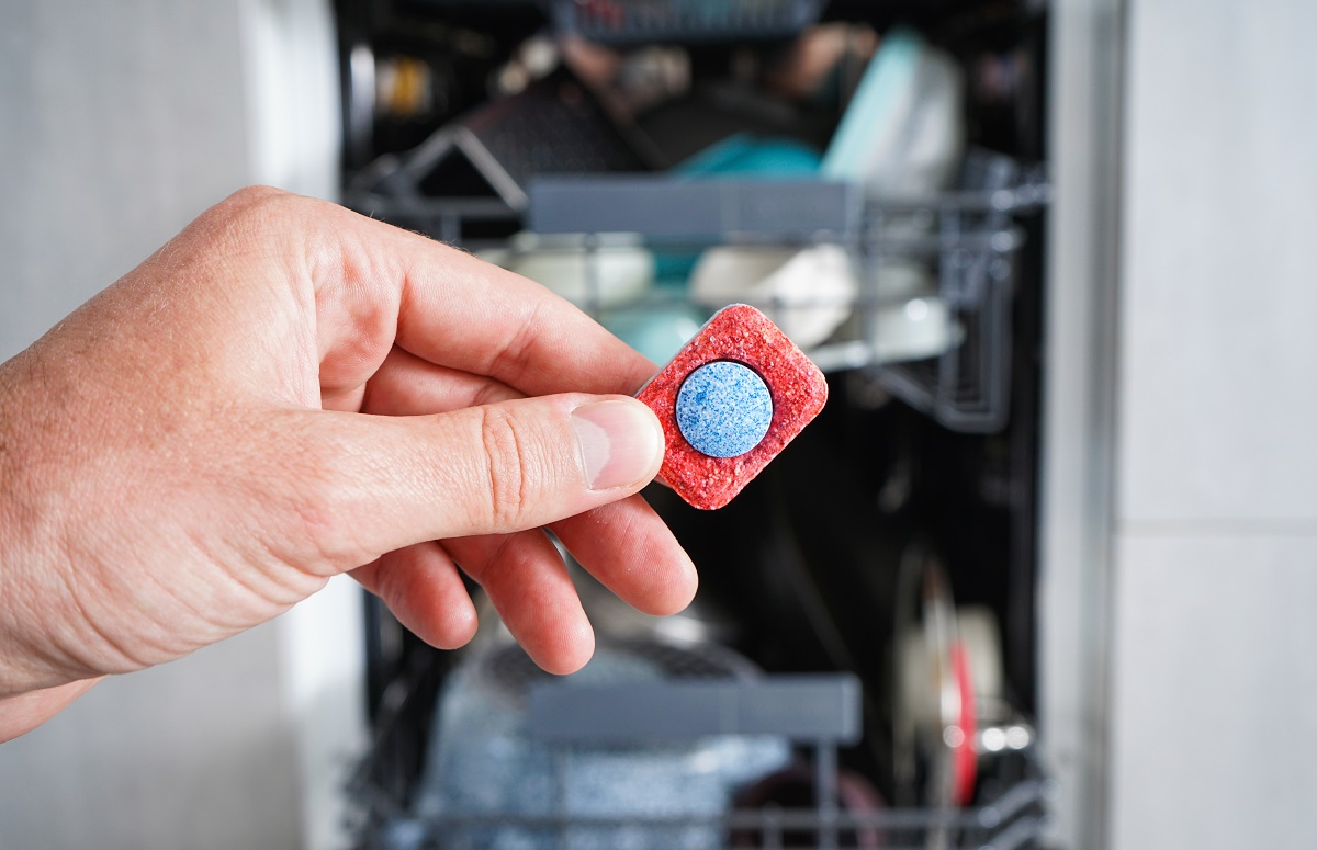 A,Man,Hand,Holding,Dishwasher,Detergent,Tablet.,Putting,Tab,Into