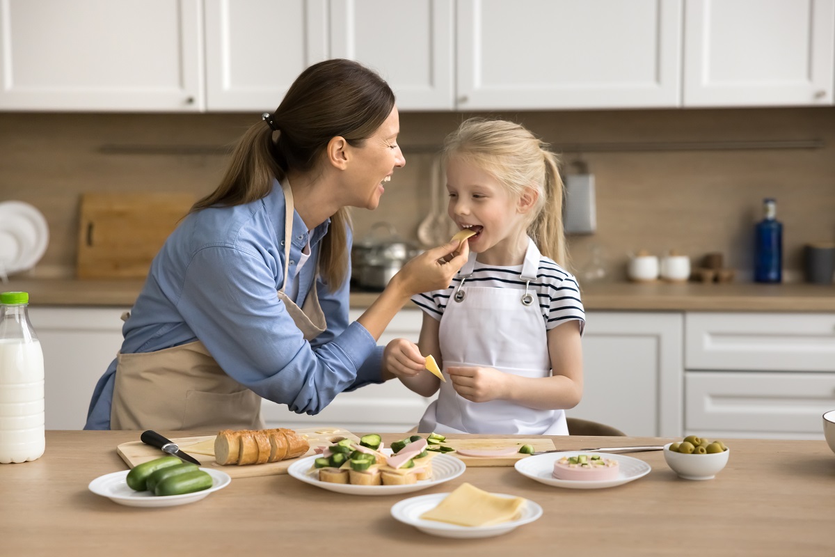 Cheerful,Mom,Feeding,Cute,Preschool,Kid,Girl,While,Cooking,In