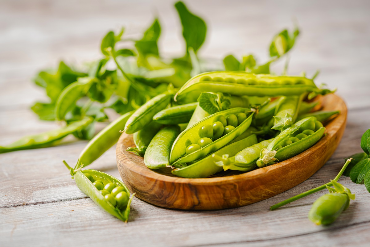 Fresh,Green,Peas,In,Wooden,Bowl,With,Pods,And,Leaves
