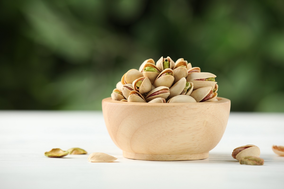 Tasty,Pistachios,In,Bowl,On,White,Wooden,Table,Against,Blurred