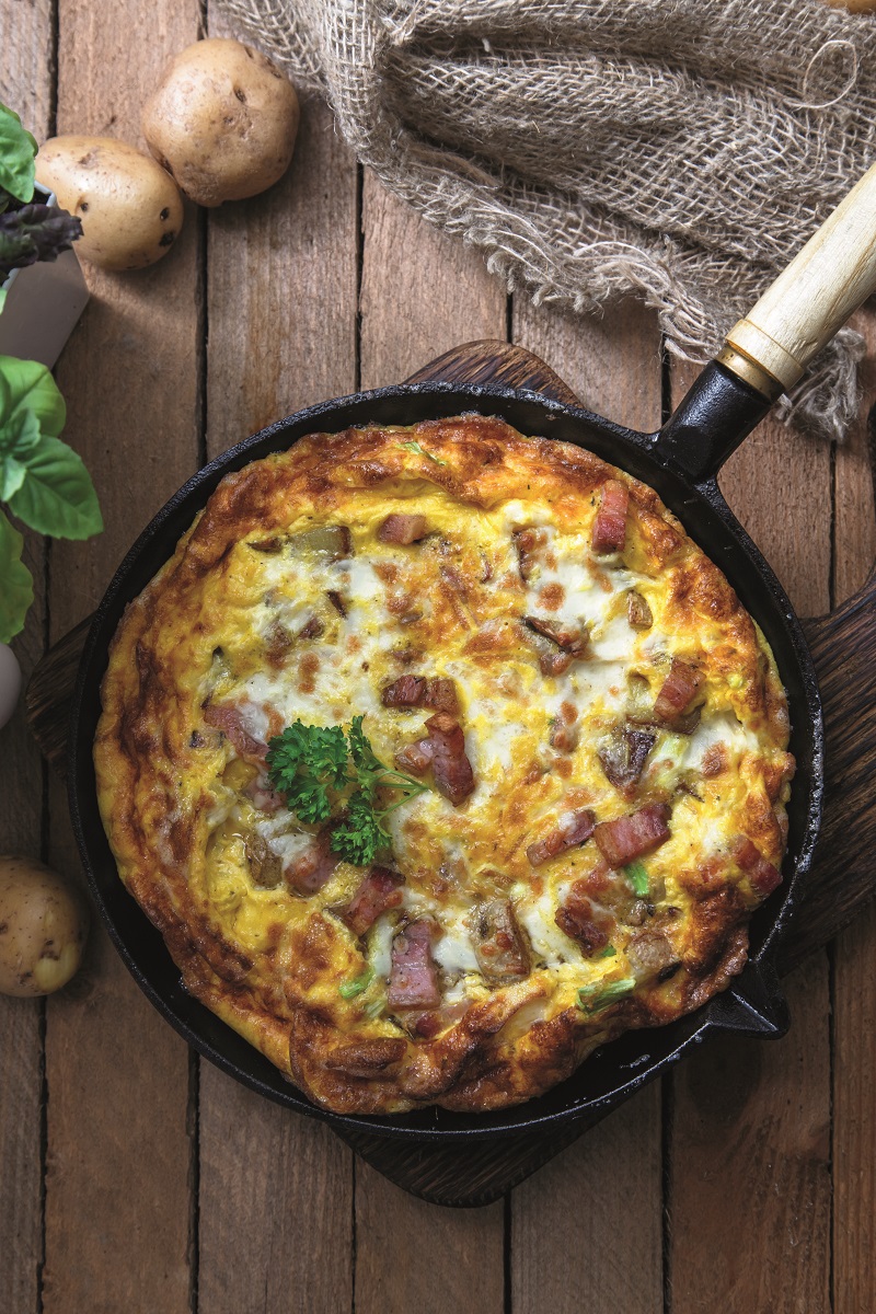 Homemade breakfast with delicious omelette filed with ham, potato and cheese, top view