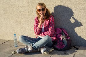 A,Young,Smiling,Cool,Girl,,Shod,On,Roller,Skates,,Sits