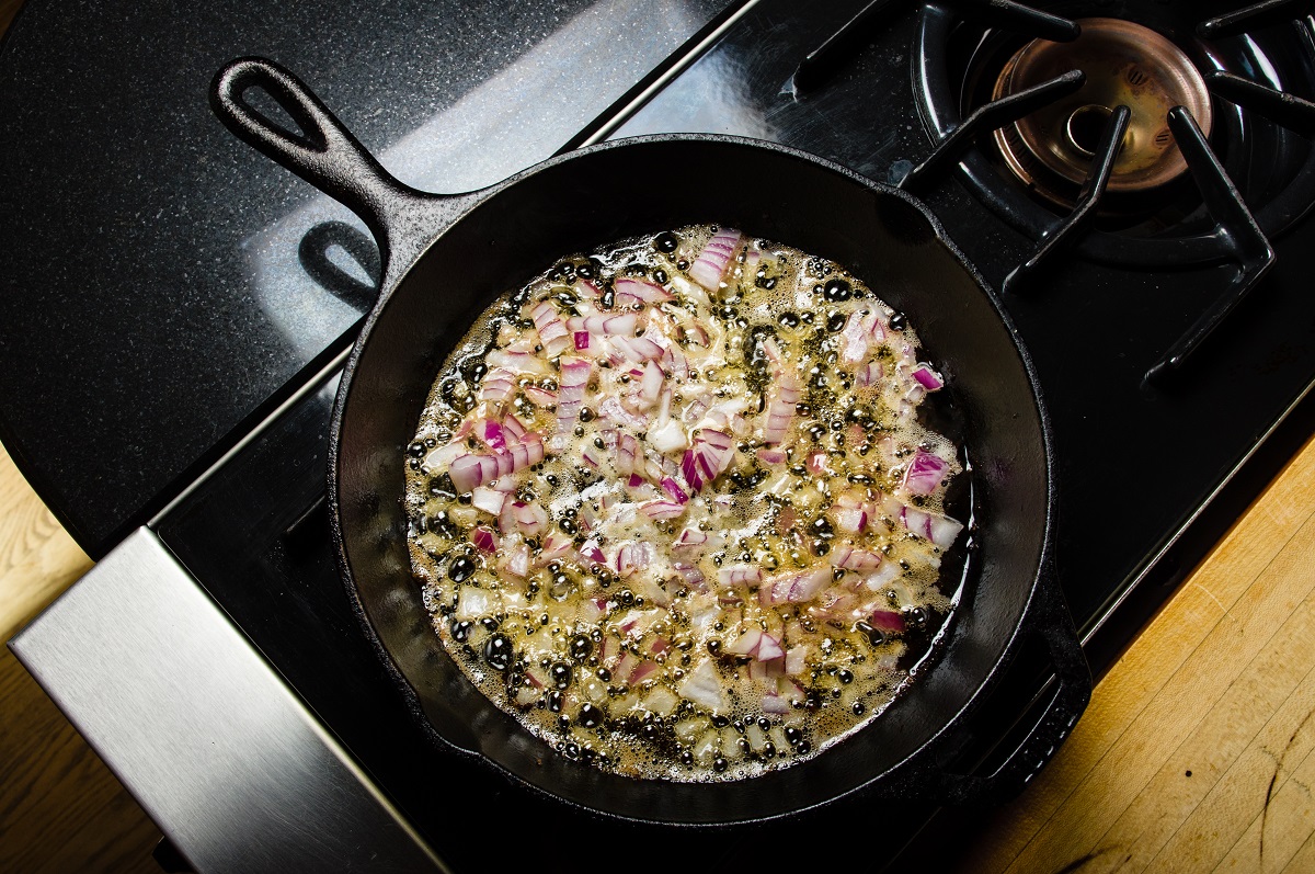 Carmelizing,Cut,Red,Onions,In,A,Cast,Iron,Skillet