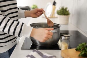 Woman,With,Wooden,Spoon,Cooking,Soup,In,Kitchen,,Closeup