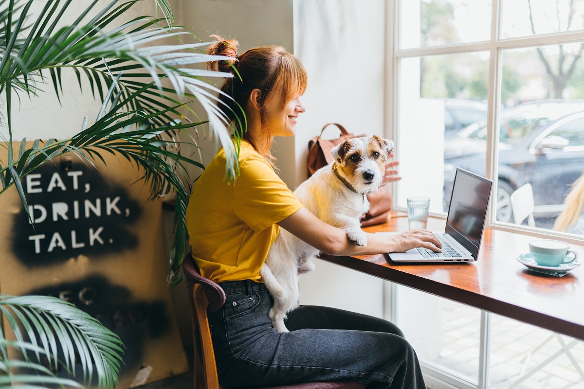 Young,Girl,Student,Sititng,At,Table,With,Computer,And,Dog