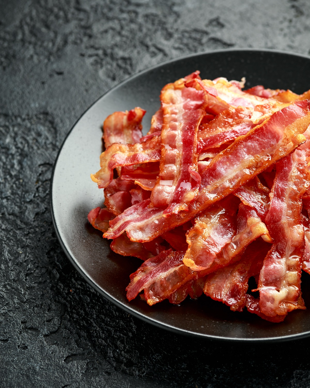 Fried,Crunchy,Streaky,Bacon,Pieces,In,A,Black,Plate