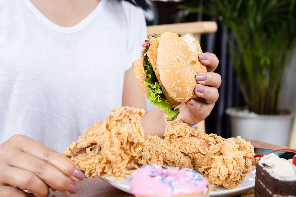 Woman,Eating,Junk,Food,,Hand,Holding,Hamburger,,Fried,Chicken,With