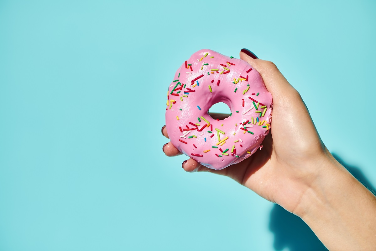 Sweet,Delicious,Donut,With,Pink,Frosting,On,It,In,Hand