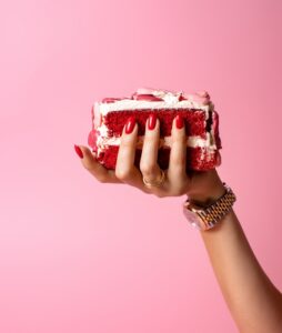 Slice,Of,Red,Velvet,Cake,In,Woman,Hand,On,Pink