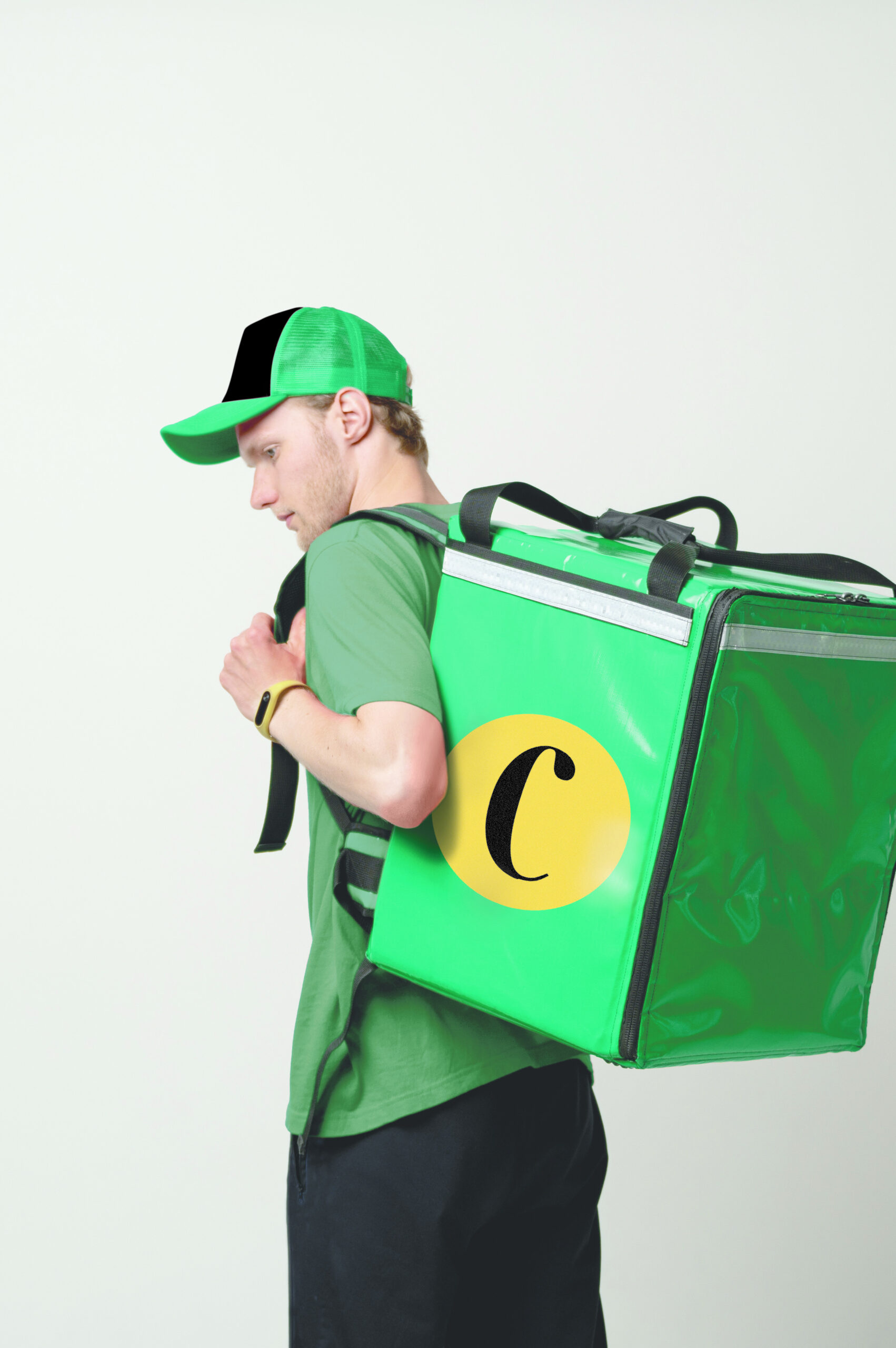 Fast Food Delivery Service Cocnept. Portrait of smiling male courier wearing red uniform holding red thermo backpack bag with a food isolated on white studio background