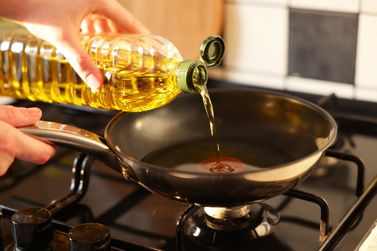 Vegetable,Fats.,Woman,Pouring,Oil,Into,Frying,Pan,On,Stove,