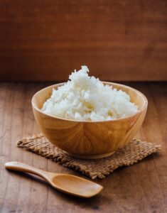 Cooked,Rice,In,Wooden,Bowl,With,Wooden,Spoon,On,Wooden