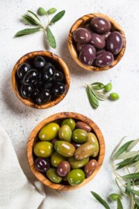 Black,And,Green,Olives,In,Wooden,Bowls,On,White,Background.