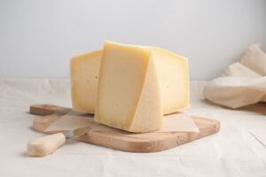 Fresh,Homemade,Cheese,With,Knife,On,Wooden,Plate,At,White