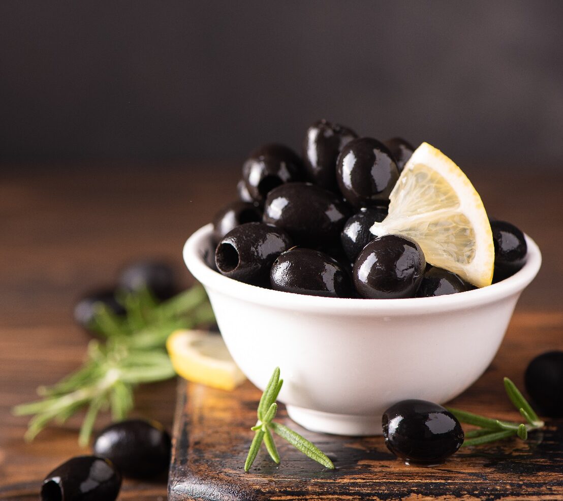 Pitted,Black,Olives,With,Lemon,In,A,White,Bowl,,Close