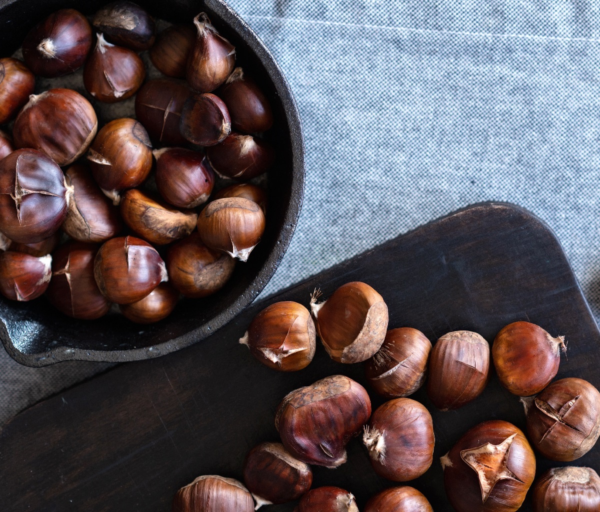 Brown,Roasted,Chestnuts,On,Black,Wooden,Board,And,In,Pan,