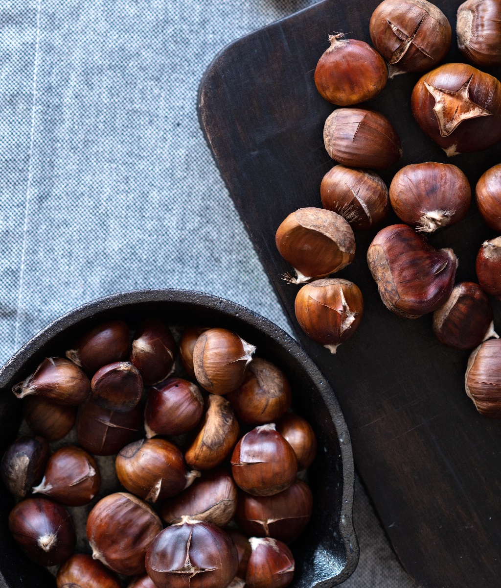 Brown,Roasted,Chestnuts,On,Black,Wooden,Board,And,In,Pan,