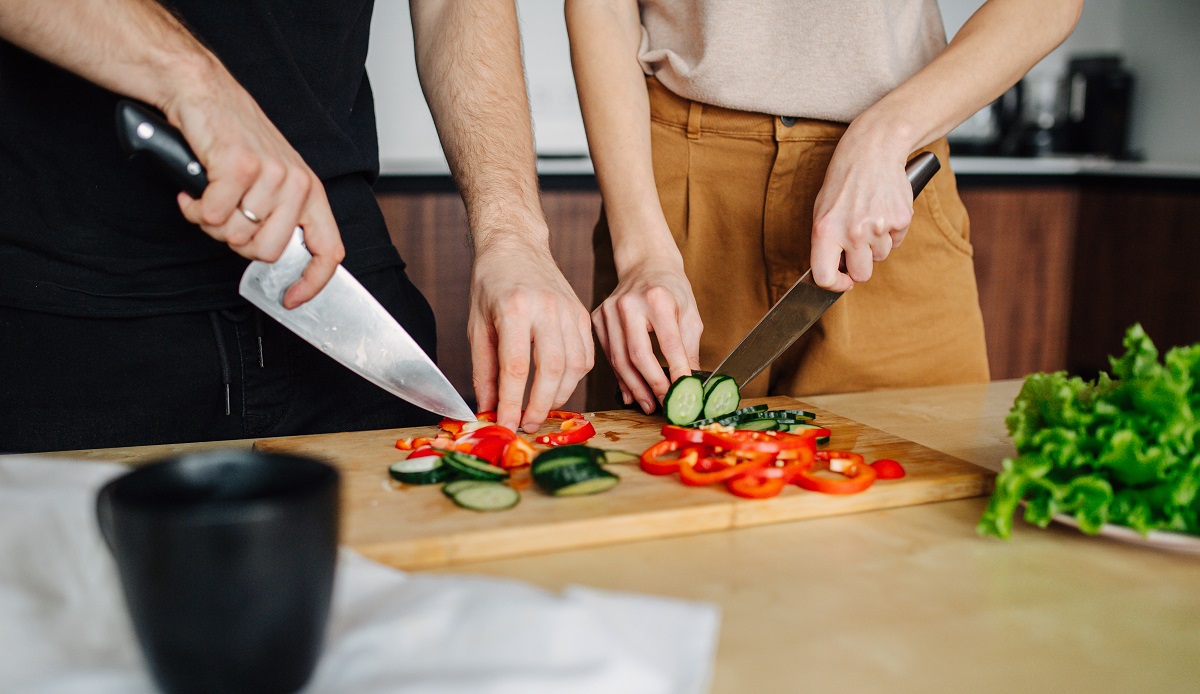 Modern,Couple,At,Home,,Busy,In,The,Kitchen,,Slicing,Vegetables.