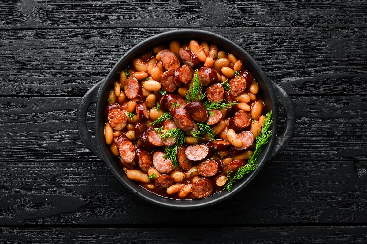 Beans,With,Sausages,In,Tomato,Sauce,On,A,Black,Plate.